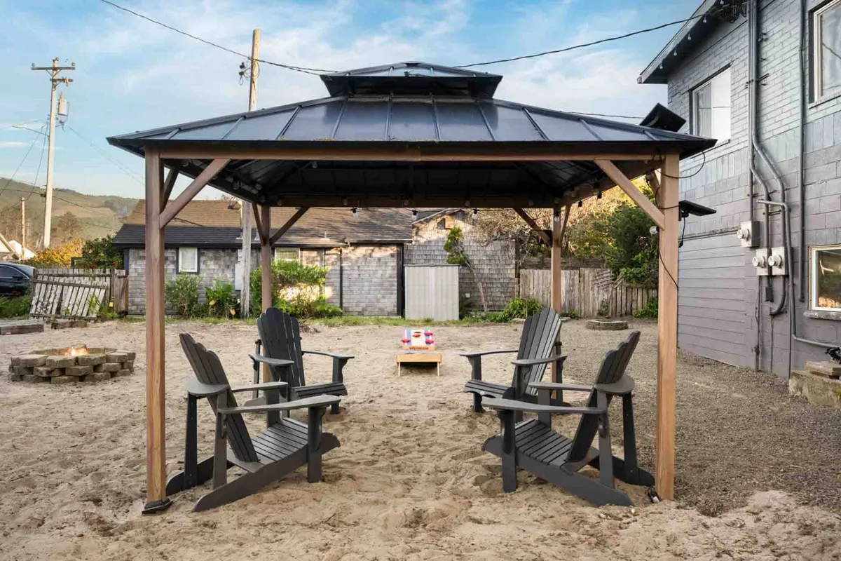 An inviting outdoor scene featuring a gazebo surrounded by Adirondack chairs and a fire pit. The setting is perfect for social gatherings, with space for relaxation, outdoor dining, and storytelling as the sun sets. The mood is welcoming and communal, ideal for groups or families.