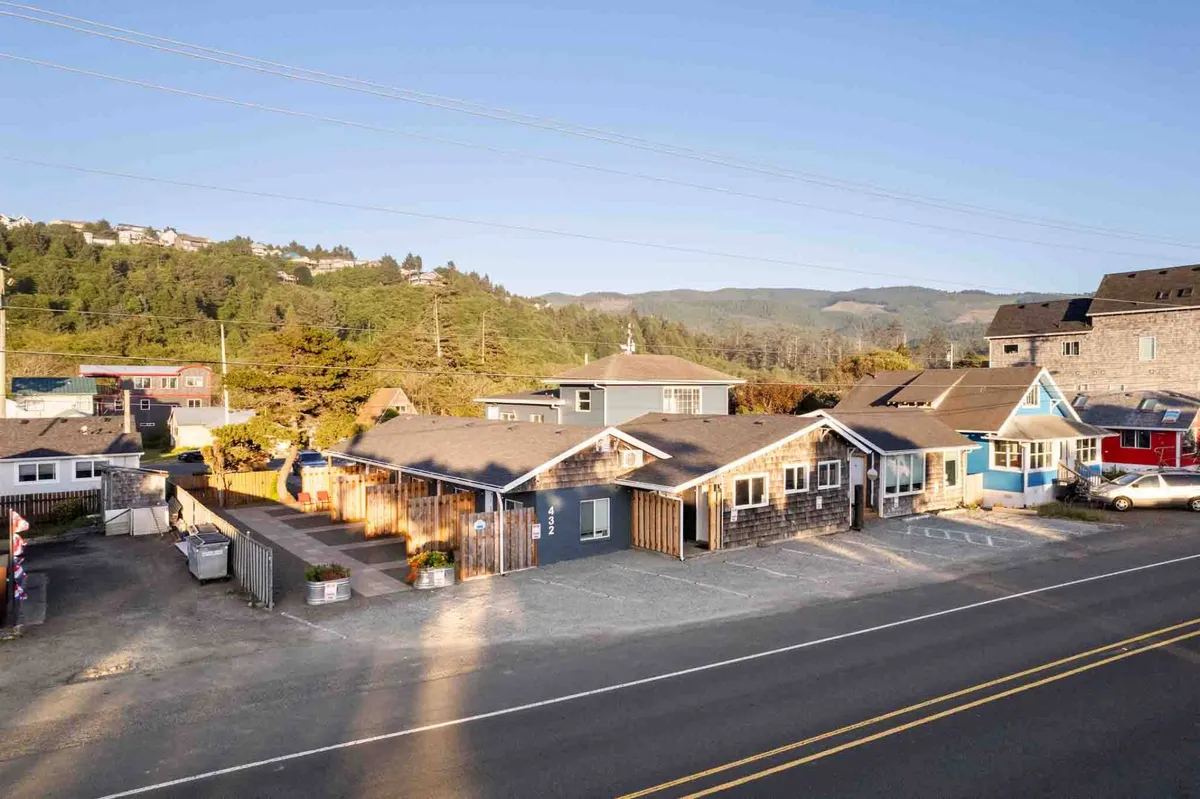 A vibrant row of colorful houses sits against a scenic mountain backdrop, with ample parking and walkways that invite guests to set out on foot. The scene suggests a lively, community-oriented environment and the ease of exploring nearby shops and attractions.
